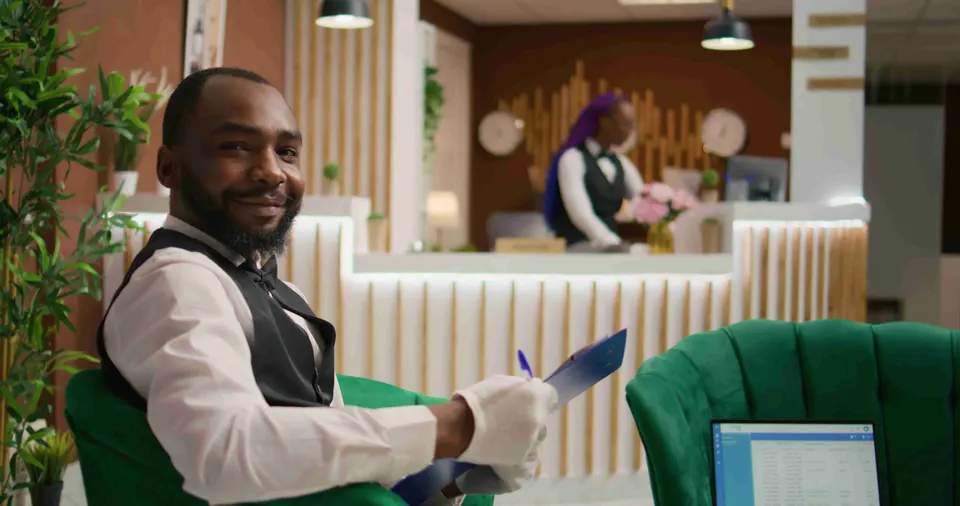 Hotel attendant filling in a paper form on a clipboard in a lobby