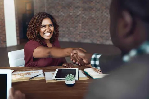 Smiling woman shaking hands across a desk
