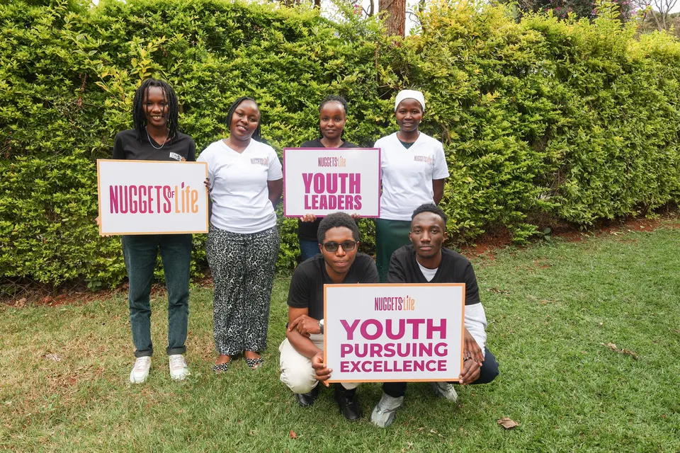 Young leaders on a lawn holding Nuggets of Life signs reading "Youth Leaders" and "Youth Pursuing Excellence"